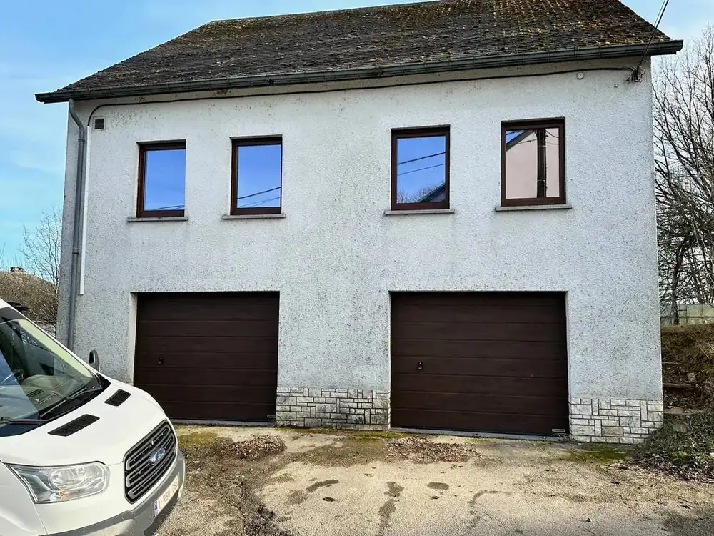 Maison rénovée — façade avant avec deux portes de garage et châssis