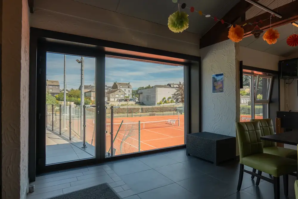 Tennis Club Bertrix — baie coulissante intérieure avec vue sur le court
